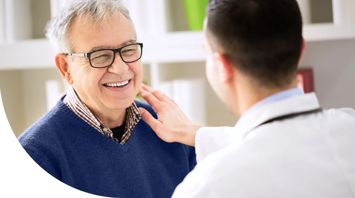 Doctor gently examining an elderly male patient during a primary care consultation