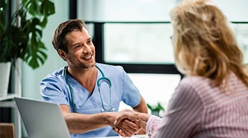 Doctor shaking hands with a female patient in a clinic